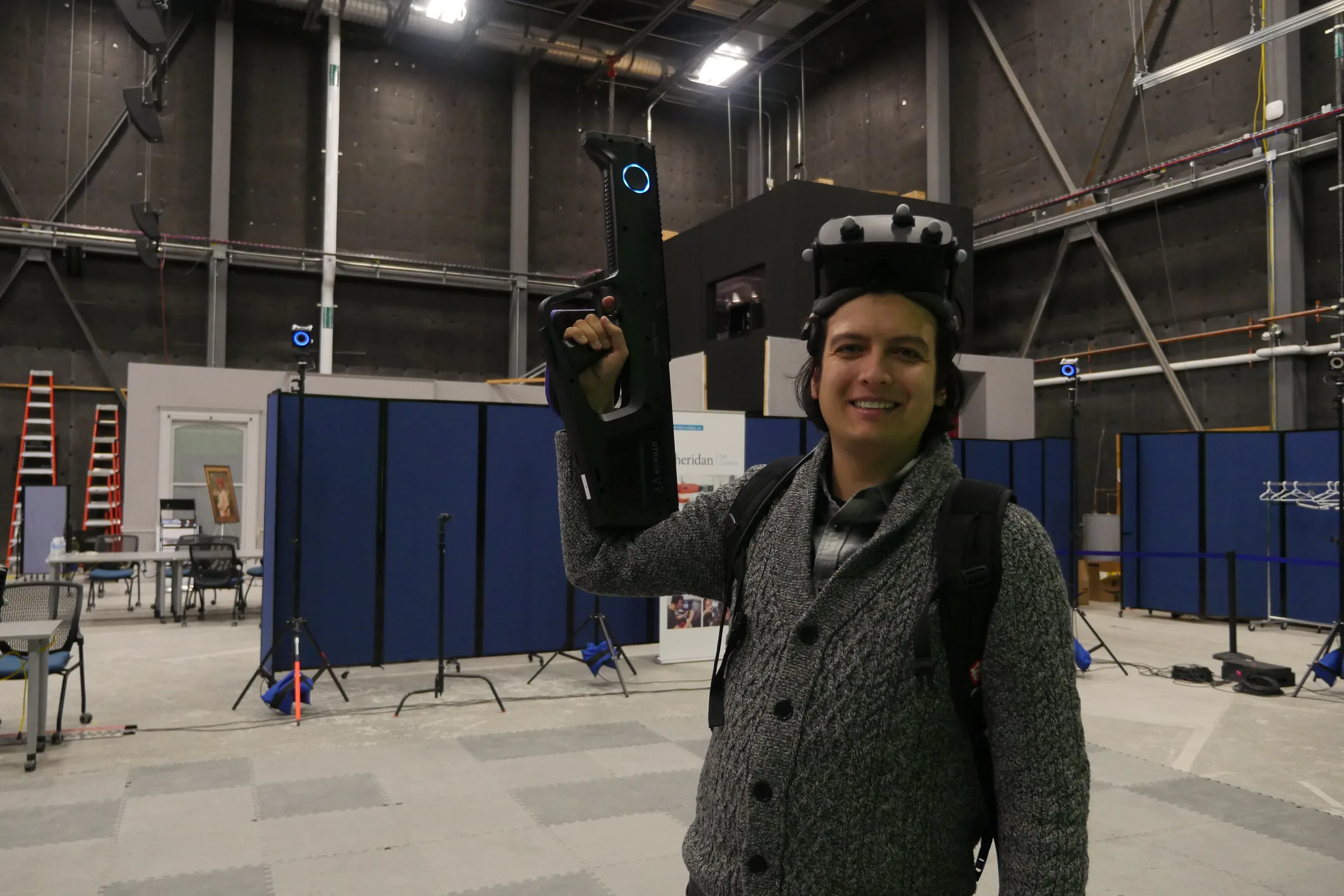Sean on a motion-capture stage wearing a tracked VR headset and holding a Striker VR haptic weapon